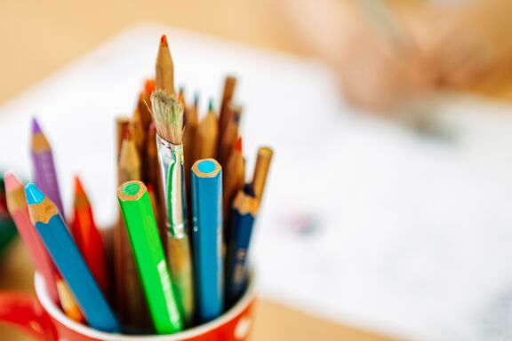 Multicolored pencils and a brush in a cup